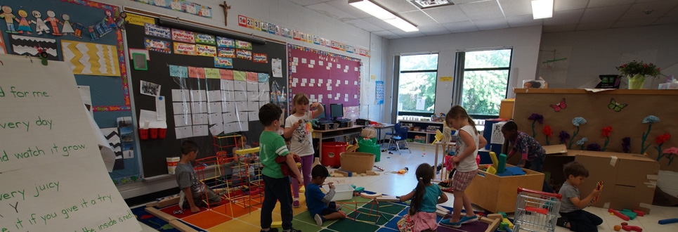 Younger students playing with toys on a classroom carpet.